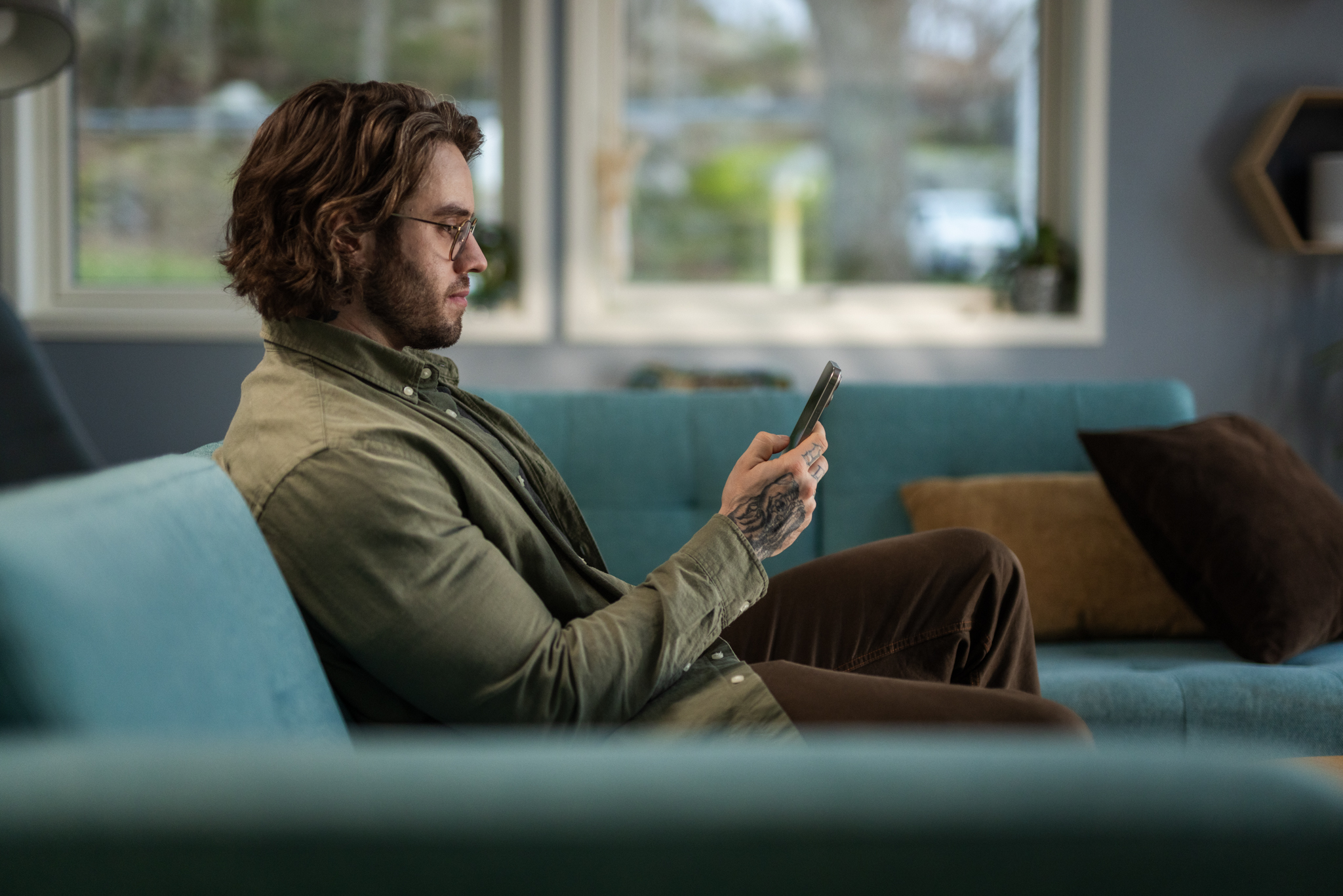 En mann som sitter i en sofa og ser på telefonen sin